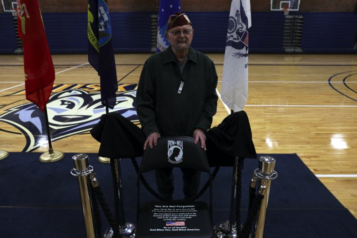 A veteran stands behind the POW/MIA chair
